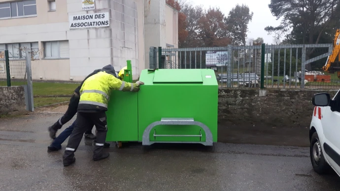 Agents déplaçant un composteur lors d'une intervention sur site